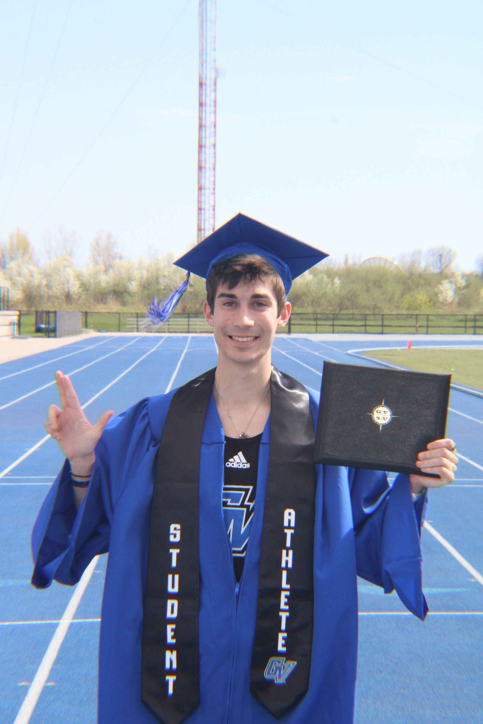 2026 PCE graduate Quinton Bauer, pictured his cap and gown while standing on a running track